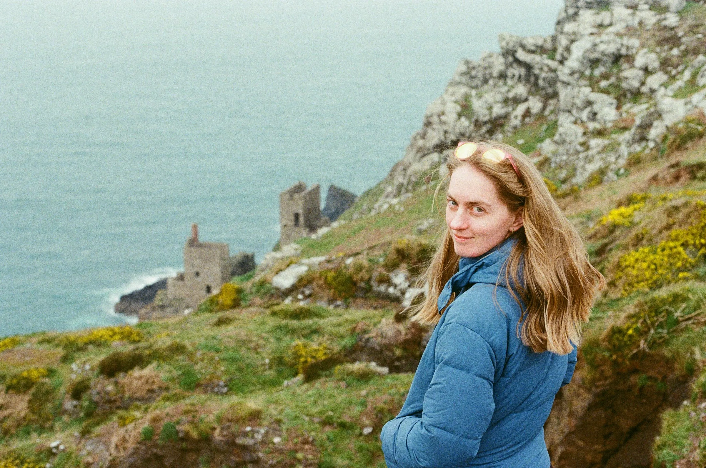 A woman in a blue jacket on a Cornish clifftop