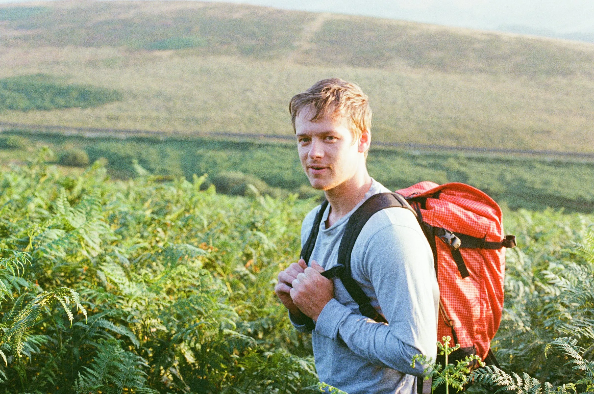 A man with a red rucksack in bracken