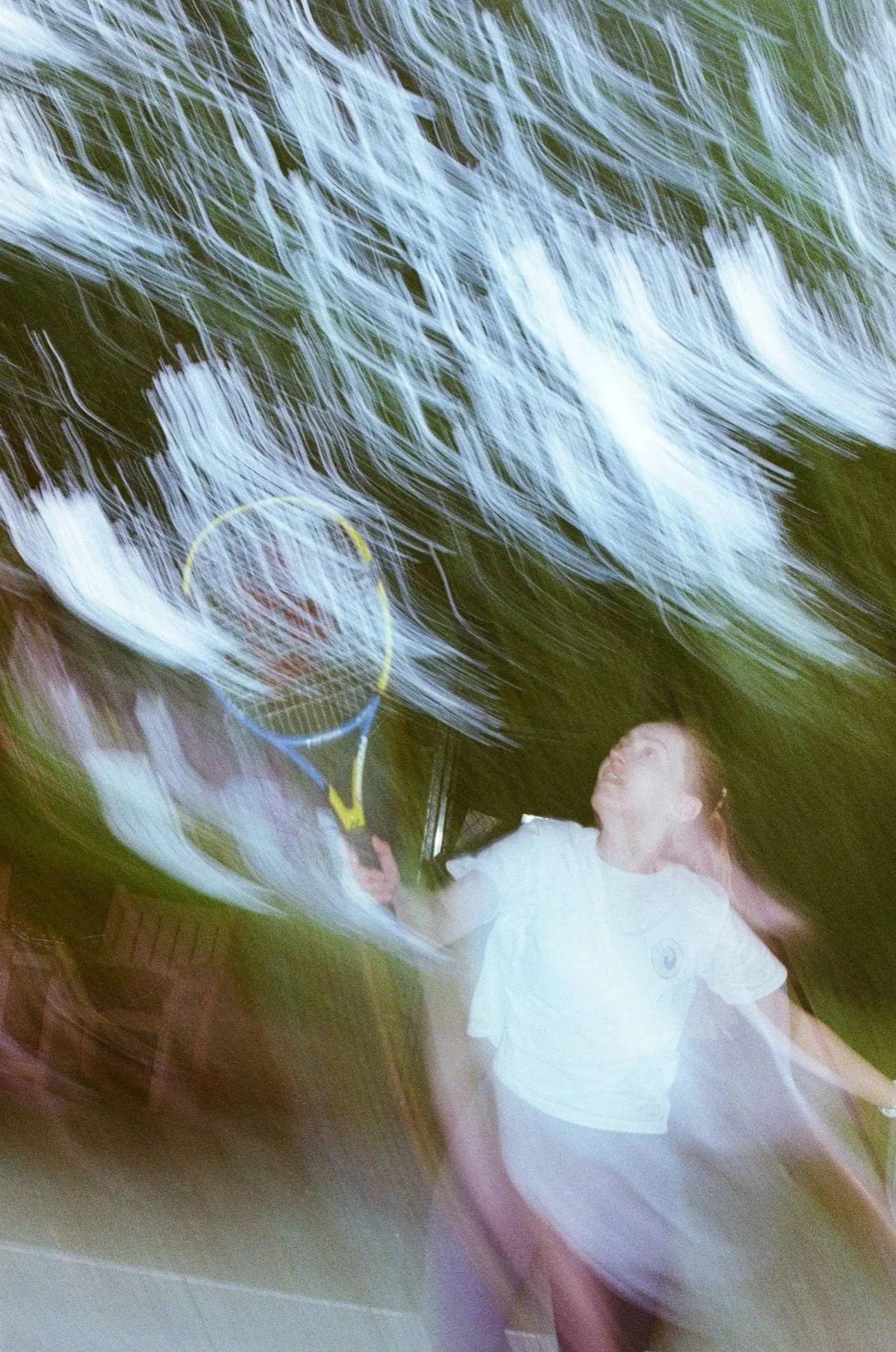 Film photograph: a tennis player mid-swing, blurred with movement